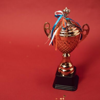 Trophy with red, white, and blue ribbons on a red background, symbolizing achievement and success in association management.