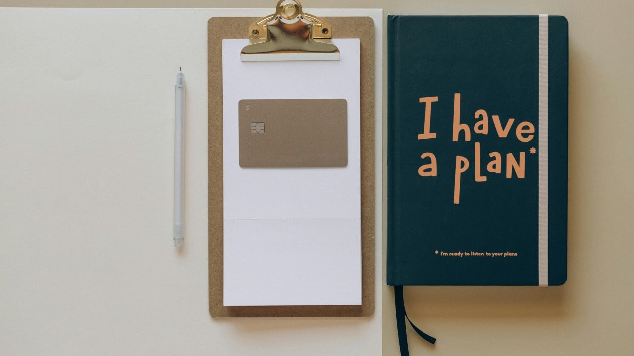 Clipboard with blank paper, a pen, a credit card, and a notebook titled "I have a plan" emphasizing budgeting and strategic planning for associations.