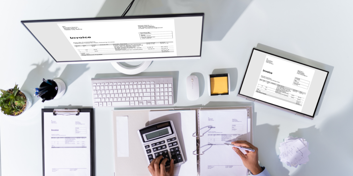 Desktop setup featuring invoices on multiple screens, calculator, and paperwork, illustrating efficient membership database management and automation in accounting for associations.