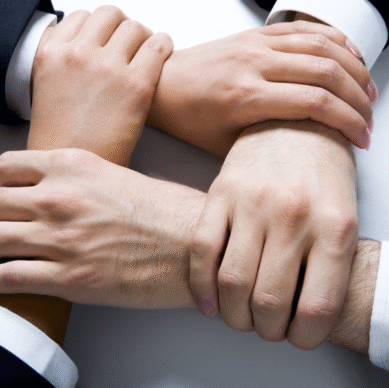 Hands of diverse individuals in business attire interlocking, symbolizing collaboration and partnership in association management.
