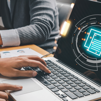 Person typing on a laptop with digital document icons, representing strategic planning and engagement for associations by NAV & Associates LLC.