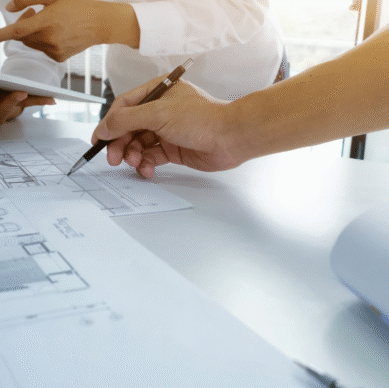 Hands discussing architectural plans on a table, emphasizing collaboration in strategic planning for associations.