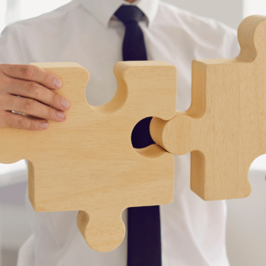 Business professional connecting wooden puzzle pieces, symbolizing strategic planning and collaboration for associations.